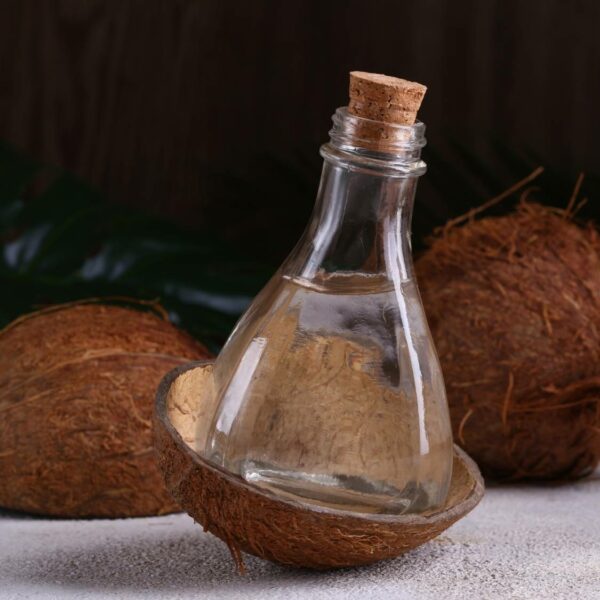 Coconuts together with coconut Oil in a transparent glass bottle