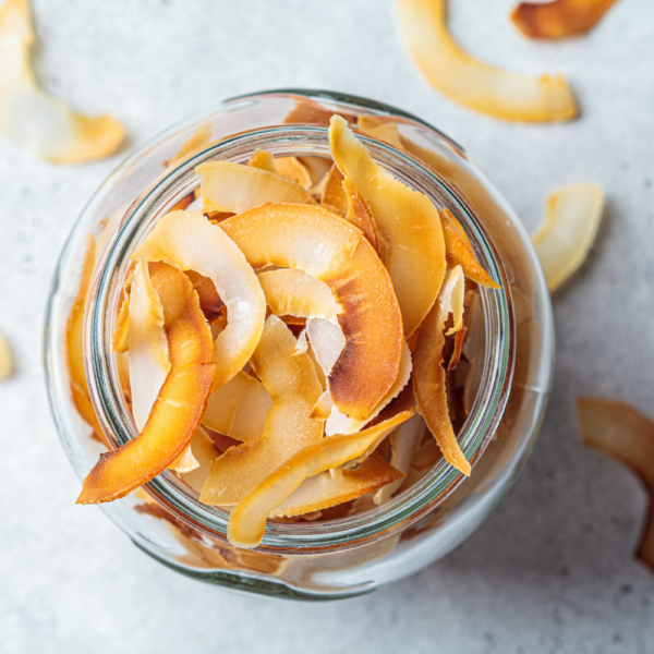Toasted, thinly sliced coconut chips in a glass jar.