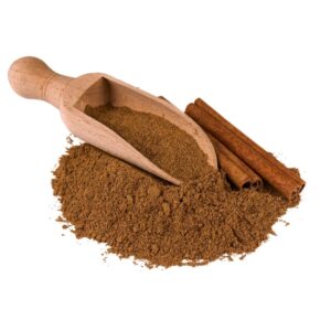 Ground cinnamon displayed with a wooden spoon and cinnamon sticks.