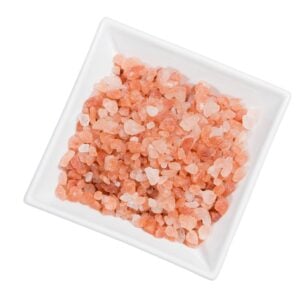 Pink granules of salt in a white, square bowl