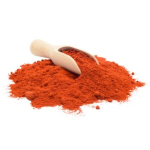 Reddish-orange powder in a heap with a scooper .