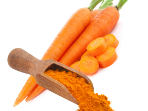 Orange powder in a scoop displayed in front of 3 carrots.