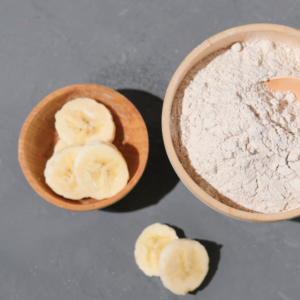 Top view of Yellowish-brown powder in a bowl beside banana slices in a bowl.