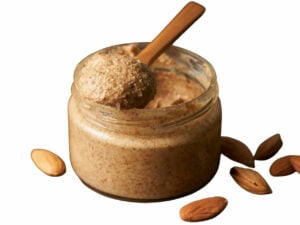 Brown nut butter in a jar, displayed with a spoon.