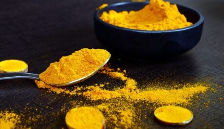 tumeric powder in a bowl and spoon on a table