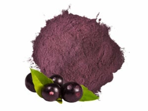 Dark purple powder in a heap, displayed with acai fruit.