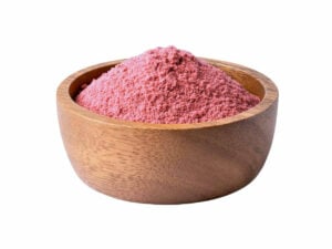 Reddish-Pink powder, heaped in a wooden bowl.