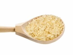 a wooden spoon with parboiled rice in it