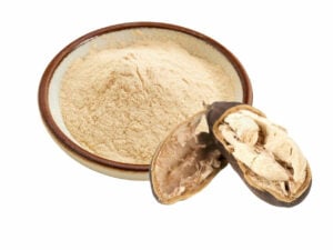 Beige powder in a bowl beside an open baobab pod.
