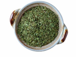 Top view of dried, green herb in a bowl